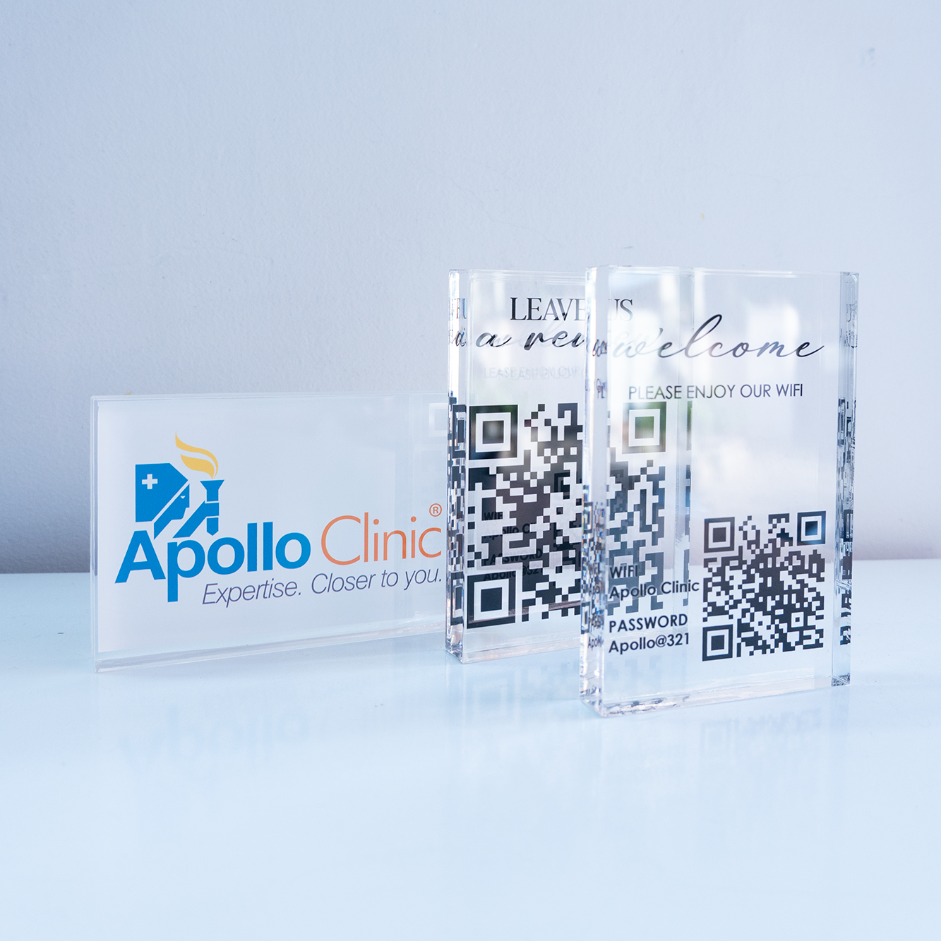 Clear glass blocks with QR codes and Apollo Clinic branding on a light blue background

